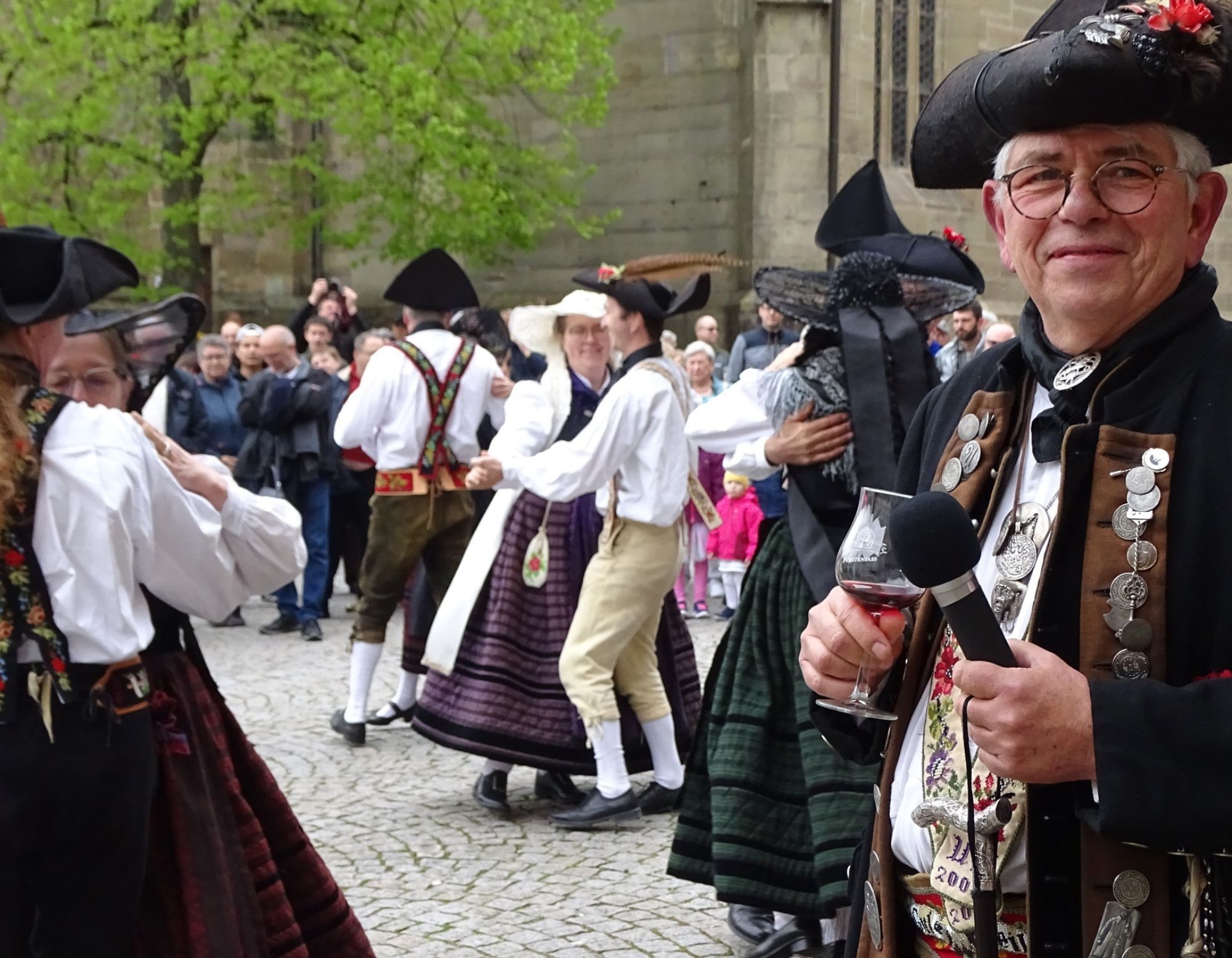 Maifeiertag_Text_2000x1555 Eine Gruppe tanzender Menschen in Tracht gekleidet.