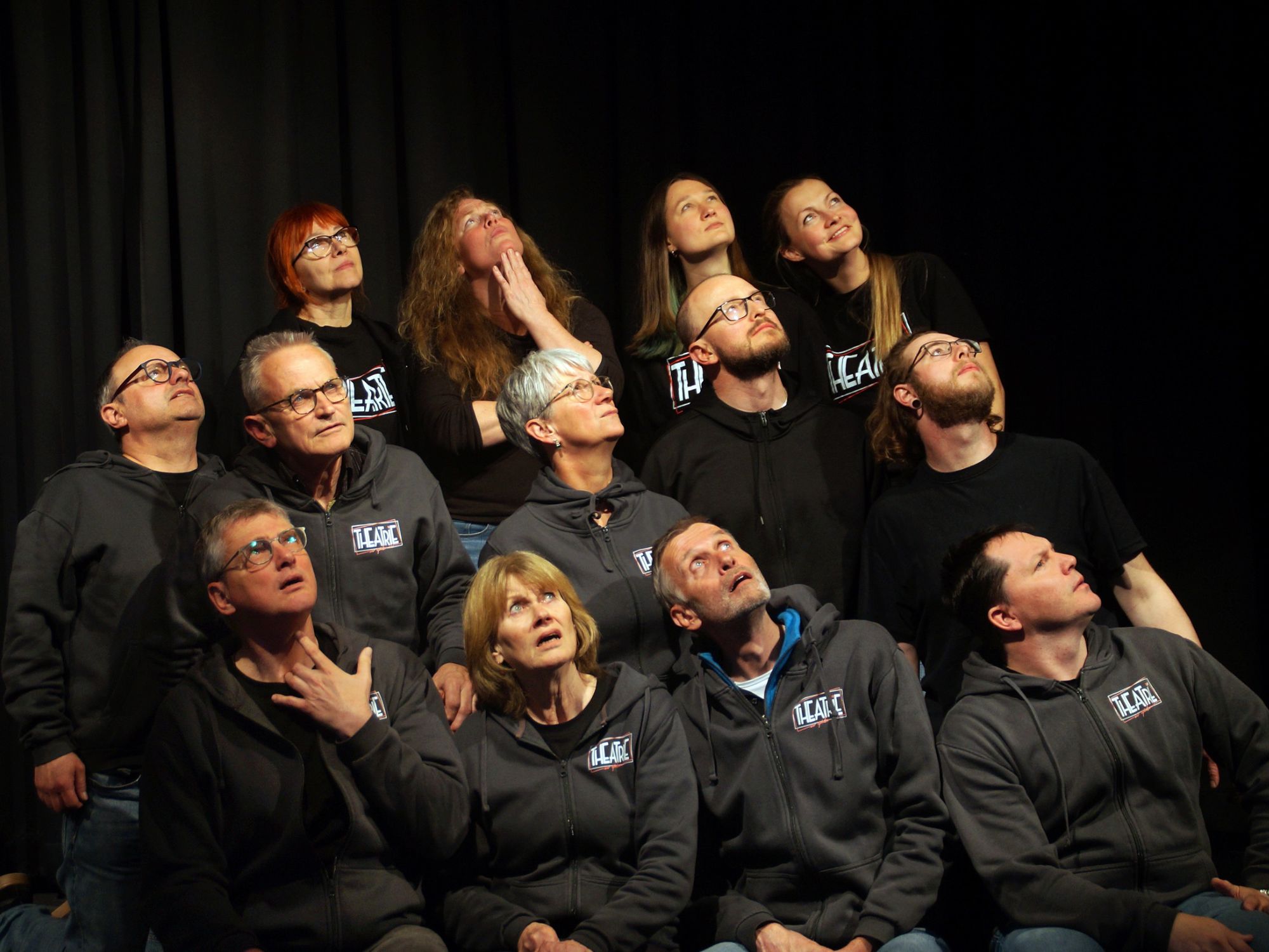 eine ganze Theatergruppe  schaut auf der Bühne nach oben