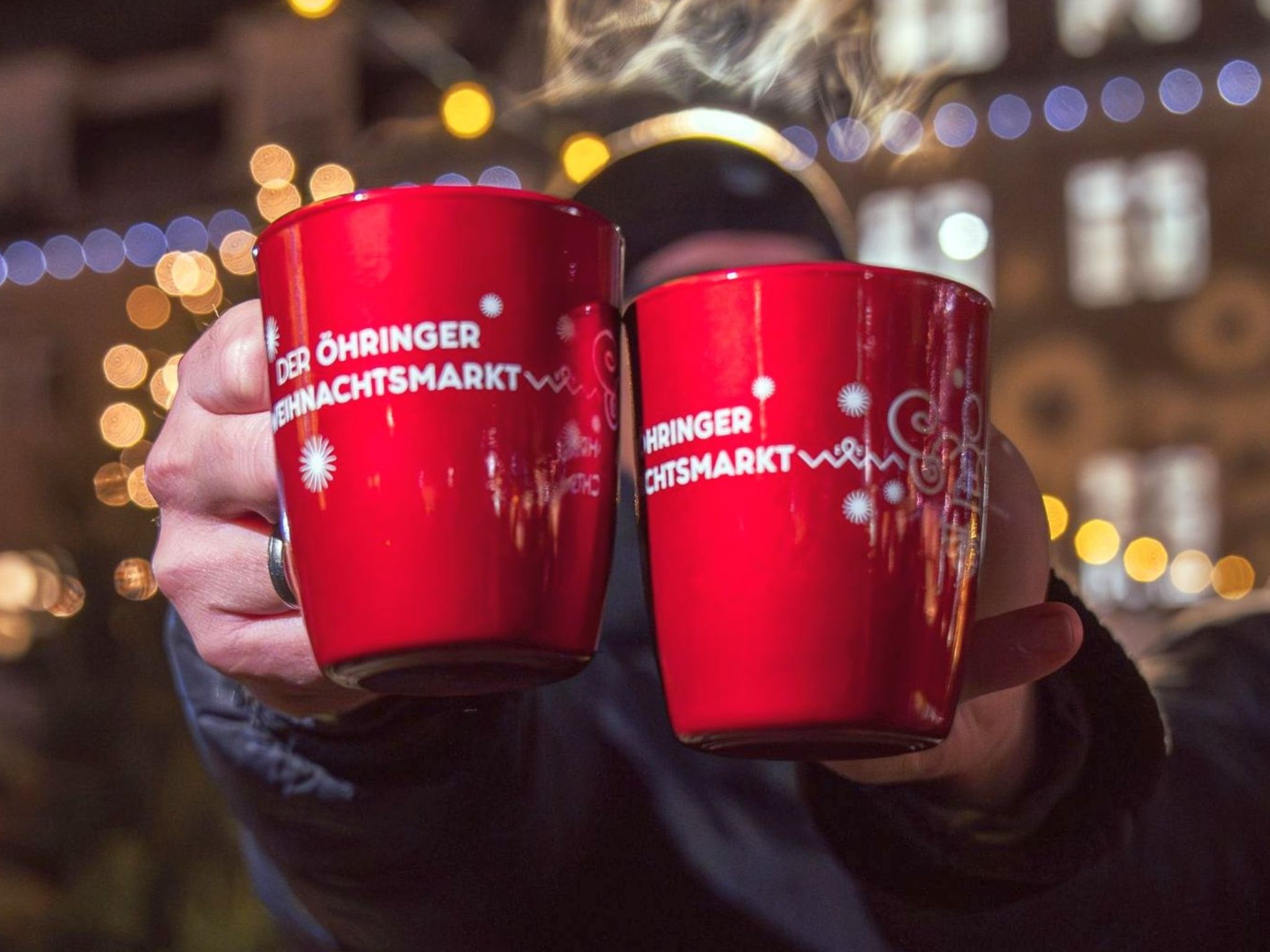 Rote Tassen auf denen das Motiv des Öhringer Weihnachtsmarkt aufgedruckt ist.