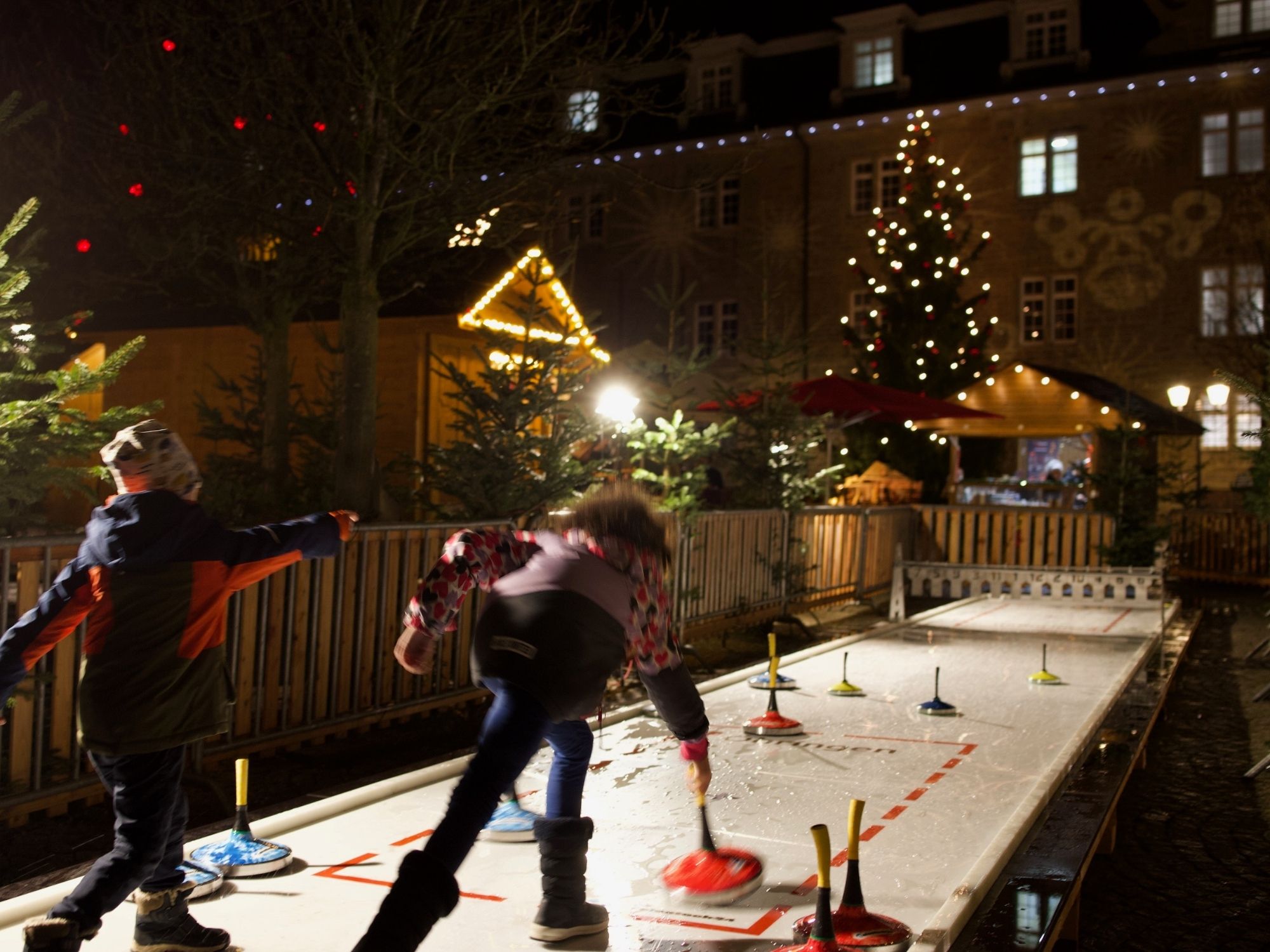 Kinder spielen auf der Eisstockbahn