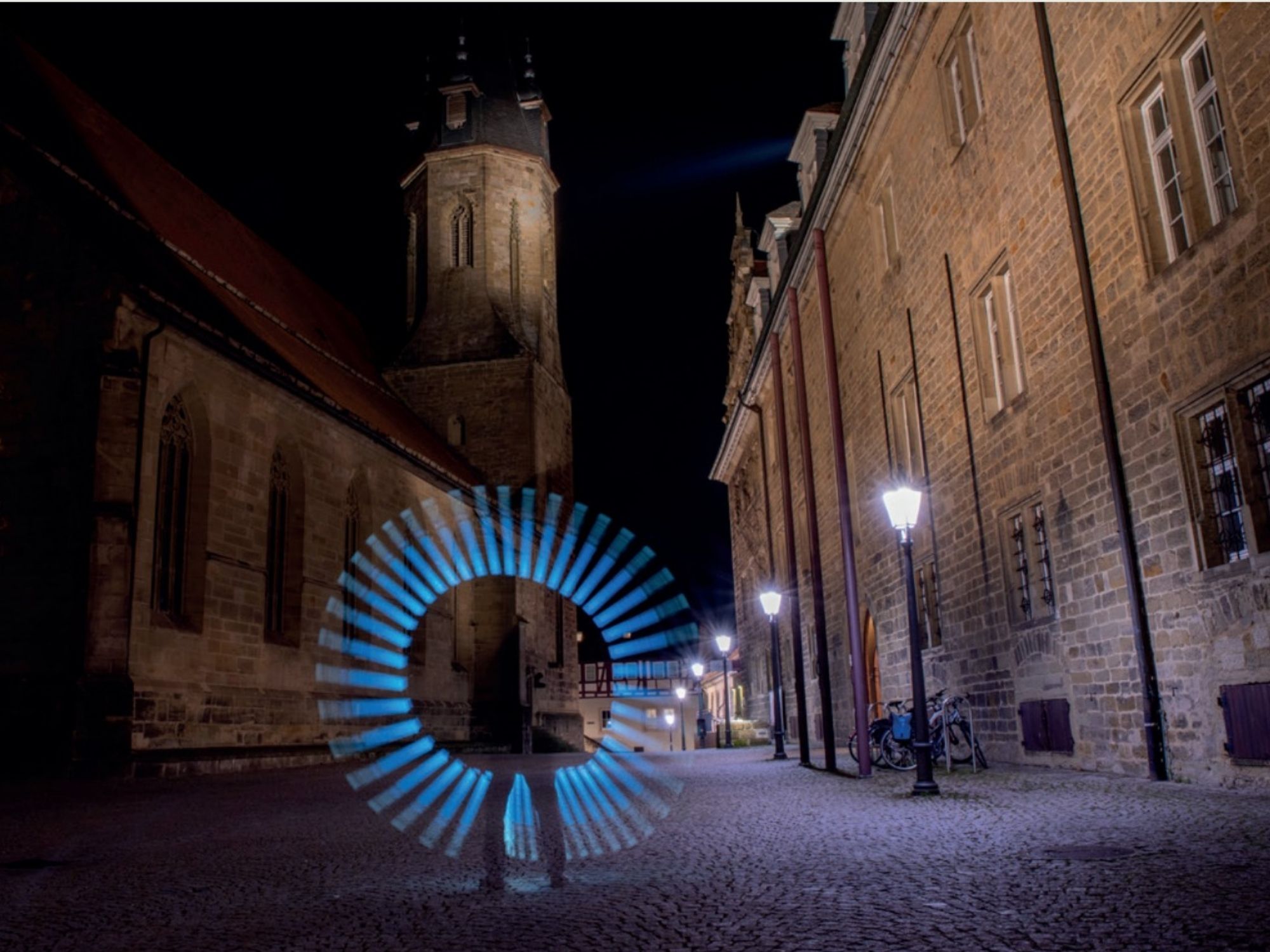 Menschliche Figur vor blauen Lichtkreisen auf dem Öhringer Marktplatz